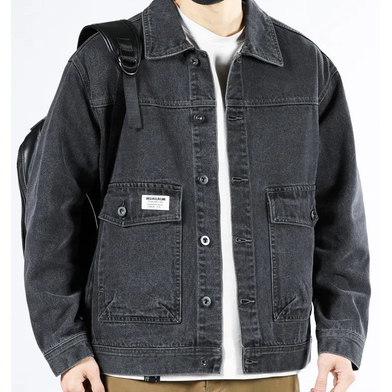 Person wearing a black denim jacket with a visible brand logo on a white background