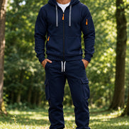 A man wearing a navy blue zip-up hoodie and matching cargo jogger pants with white sneakers, 