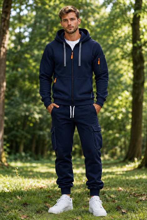 A man wearing a navy blue zip-up hoodie and matching cargo jogger pants with white sneakers, 
