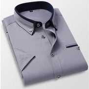 Folded gray dress shirt with navy collar and trim on a light gray background