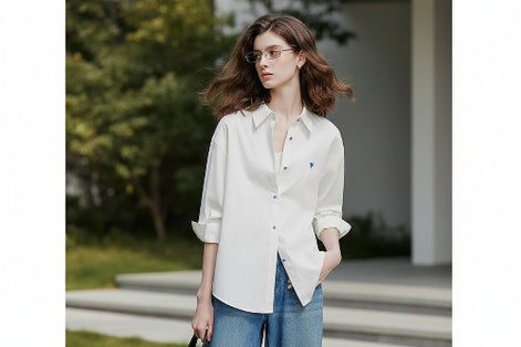 Woman wearing a white shirt with rolled-up sleeves and blue jeans on a plain background
