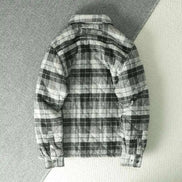 A black and white plaid flannel shirt jacket shown from the back, laid flat on a textured gray surface.