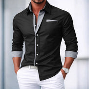 Man wearing a navy button-up shirt with light gray trim and white pants against a blurred background