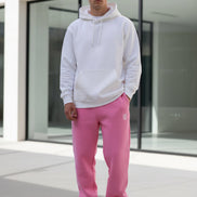 Person wearing pink sweatpants with a logo in a minimal indoor setting
