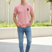 Pink t-shirt with a small brown patch on a hanger against a light background