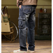 Rear-angle view of a model wearing faded dark blue cargo pants with a large flap thigh pocket and decorative stitching on the back pockets, paired with light-colored sneakers.