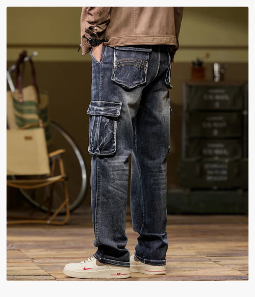 Rear-angle view of a model wearing faded dark blue cargo pants with a large flap thigh pocket and decorative stitching on the back pockets, paired with light-colored sneakers.