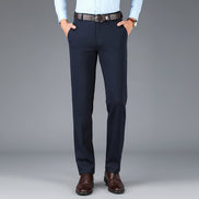 Navy blue dress pants with a brown belt on a gray background