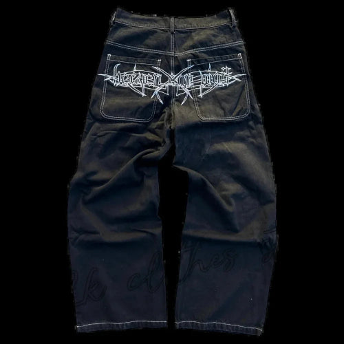 Back view of black wide-leg jeans laid flat, featuring white contrast stitching and a large white gothic lettering graphic across both back pockets.
