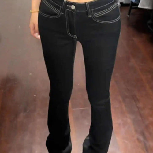 Person wearing a black top and black jeans in a fitting room.