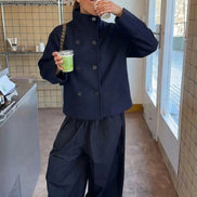 Woman wearing a navy stand-collar short coat while holding drinks in a café