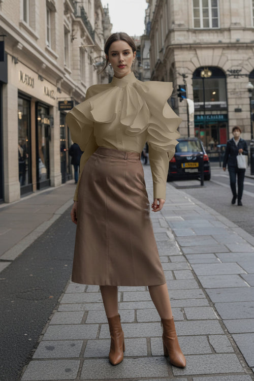 Person wearing a beige blouse with ruffled sleeves on a city street.