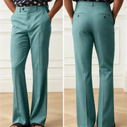 A side-by-side front and back view of a person wearing high-waisted, wide-leg teal trousers. The model is also wearing a navy blouse with white polka dots and black slide sandals, 