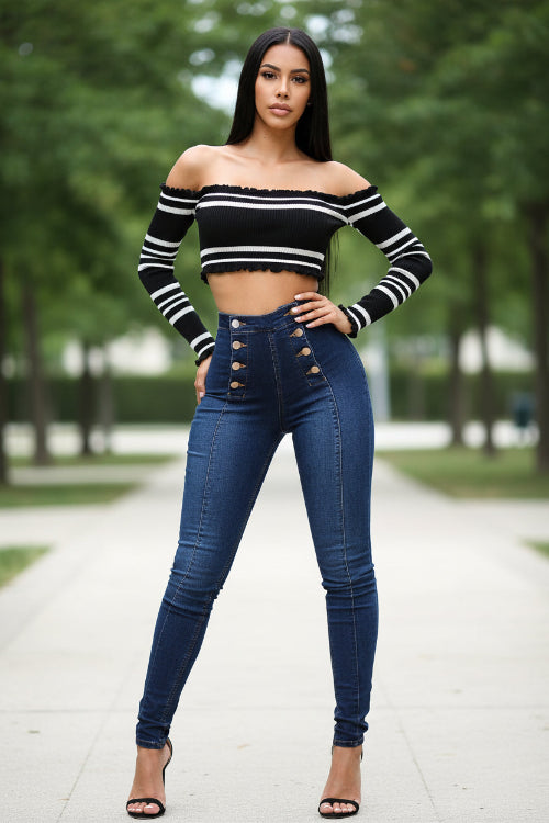 Woman wearing a black and white striped off-shoulder top and blue jeans 