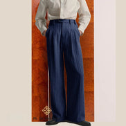 Person wearing a white shirt and blue striped pants against a wooden panel background