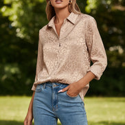 Woman wearing a beige leopard print shirt and blue jeans against a light gray background