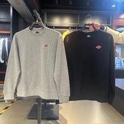 Gray and black sweatshirts with a logo on hangers in a store setting.