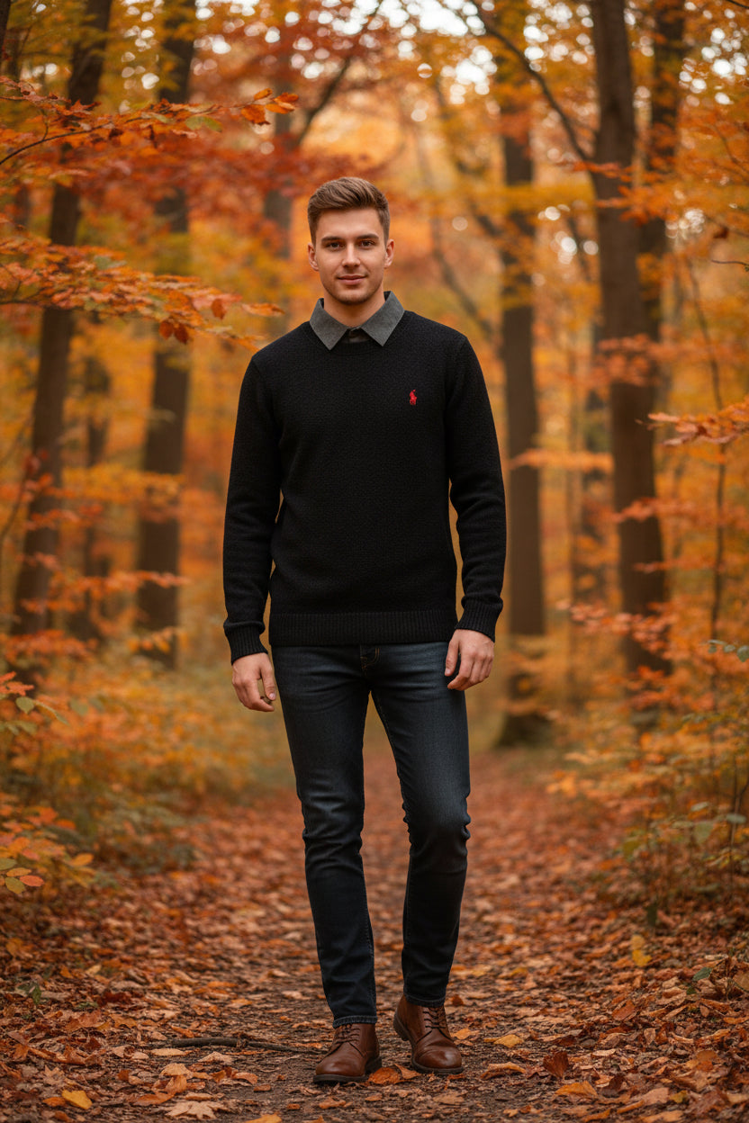 Black sweater with a collar held up against a rack of sweaters.