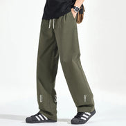Model wearing army green loose-fit straight-leg pants with a white drawstring waist and side pockets, shown from the front with black sneakers.