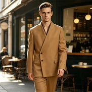 A man wearing a camel brown double-breasted suit with a unique wrap-style collar, walking on a city street in front of a cafe.