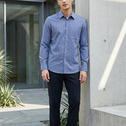 A row of long-sleeve button-up shirts hanging on wooden hangers against a dark gray gradient background. The shirts are shown in multiple colors, including slate 