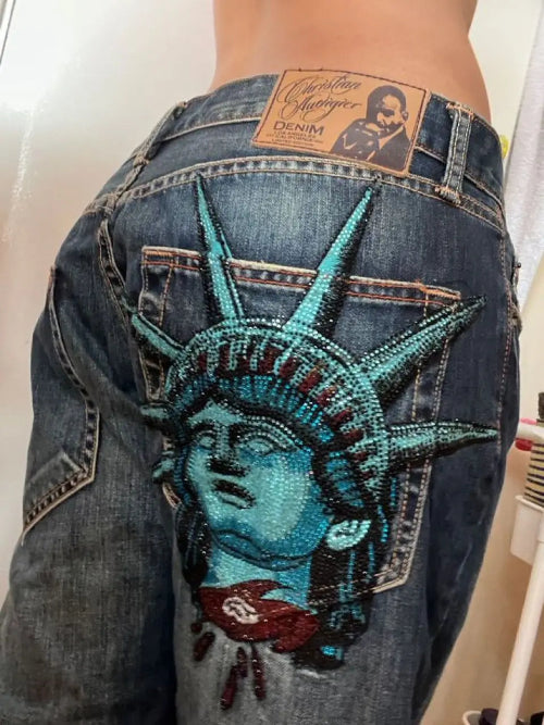 Blue jeans with a beaded Statue of Liberty design on the back pocket.