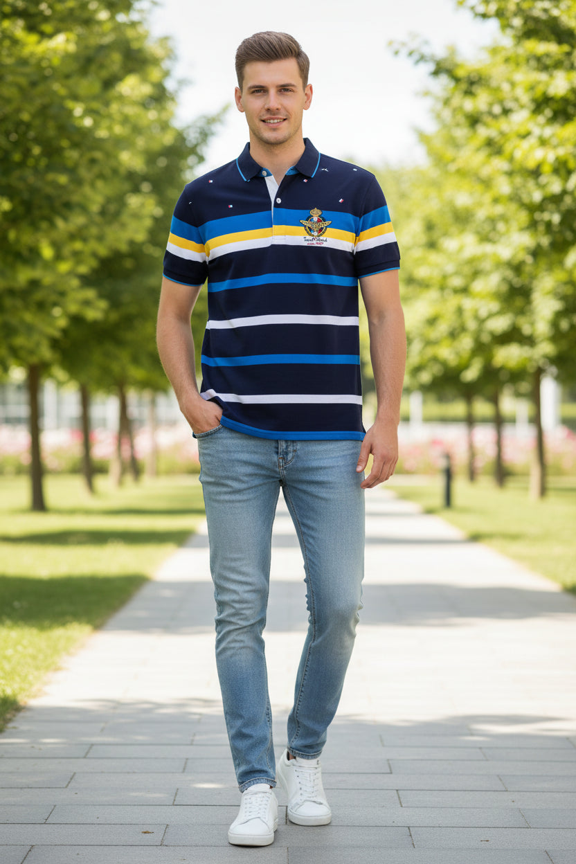 A short-sleeve polo shirt with horizontal navy, blue, yellow, and white stripes, featuring a gold and white military-style crest on the left chest. The shirt is displayed flat against a white background with a TACE&SHARK brand logo in the top-left corner.