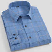 A folded light blue long-sleeve plaid dress shirt with a pointed collar and dark buttons, shown on a clean white background.