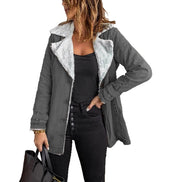 Woman wearing a gray jacket with white fleece-look lining, wide lapels and buckled cuffs over a black top and jeans