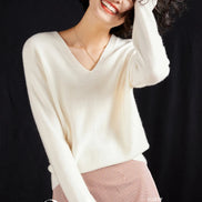 Woman wearing a white cashmere sweater with a black background