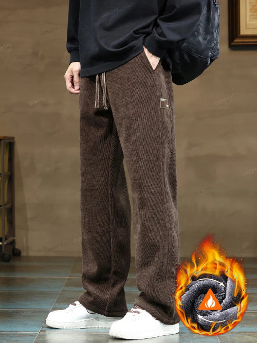 Person wearing brown corduroy pants with a flame graphic in the corner