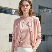 Mannequin wearing a pink cardigan and white pants against a neutral background