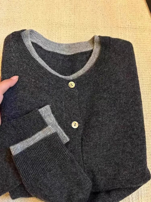 Folded dark gray sweater with light gray trim on a beige surface