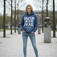 Blue hoodie with 'Faith Over Fear' text on a wooden surface