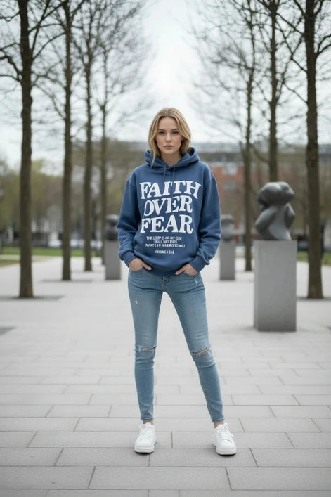 Blue hoodie with 'Faith Over Fear' text on a wooden surface