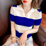 A woman wearing a short-sleeve collared knit top with bold horizontal stripes in royal blue and off-white, seated in a brown leather chair.