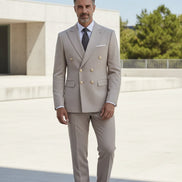 Man wearing a beige suit with gold buttons on a gray background