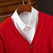 Red cardigan over a white shirt on a wooden hanger against a dark background