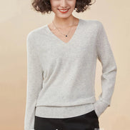 Woman wearing a gray cashmere sweater with a beige background