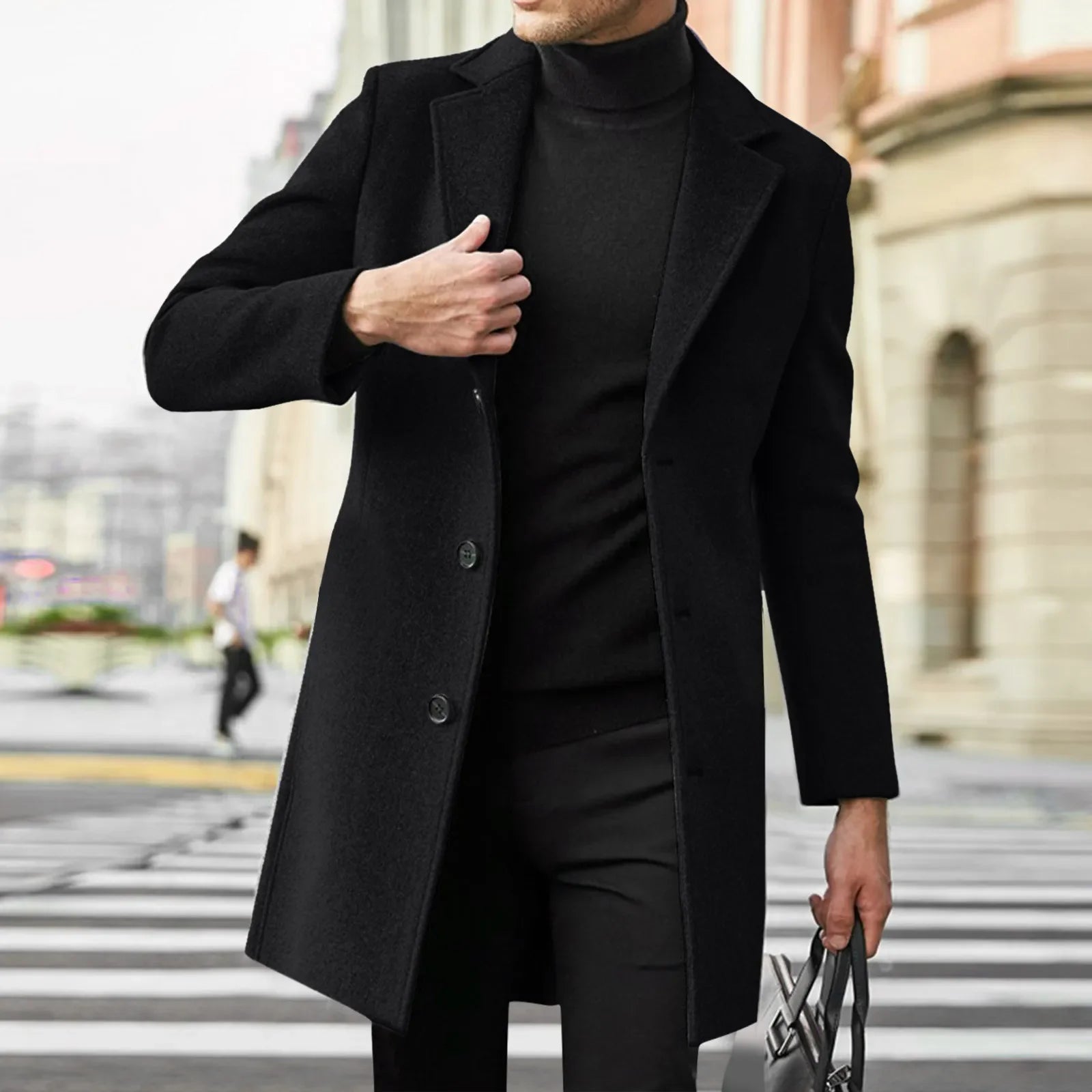 Person wearing a black coat and turtleneck standing on a city street.