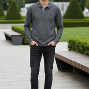 Gray polo shirt on a hanger with a brand logo in front of other colored shirts.