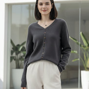 Person wearing a gray cardigan with buttons in a clothing store.