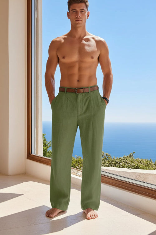 Person wearing green pants with a brown belt, standing by a window with a view of the ocean.