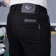 Close-up rear view of a person wearing black jeans with a textured triangular patch on the back waistband and a small vertical brand tab 