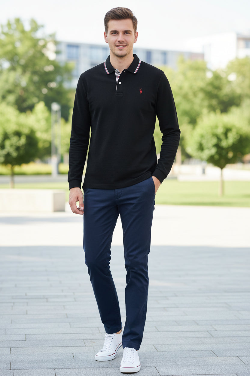 Black polo shirt with a red logo held by a hand, with other shirts in the background.