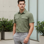 Man wearing a green short-sleeve shirt with pockets on a white background