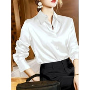 White satin button-down shirt worn by a model with black pants and a black bag.