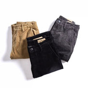 Three pairs of folded corduroy pants in tan, black, and charcoal gray, arranged on a clean white background.
