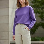 A solid purple crewneck sweatshirt with long sleeves and ribbed cuffs and hem, laid flat on a white background with a soft drop shadow.