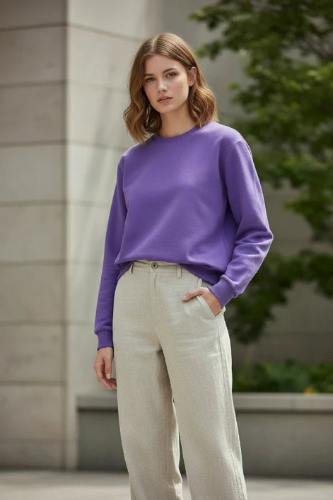 A solid purple crewneck sweatshirt with long sleeves and ribbed cuffs and hem, laid flat on a white background with a soft drop shadow.
